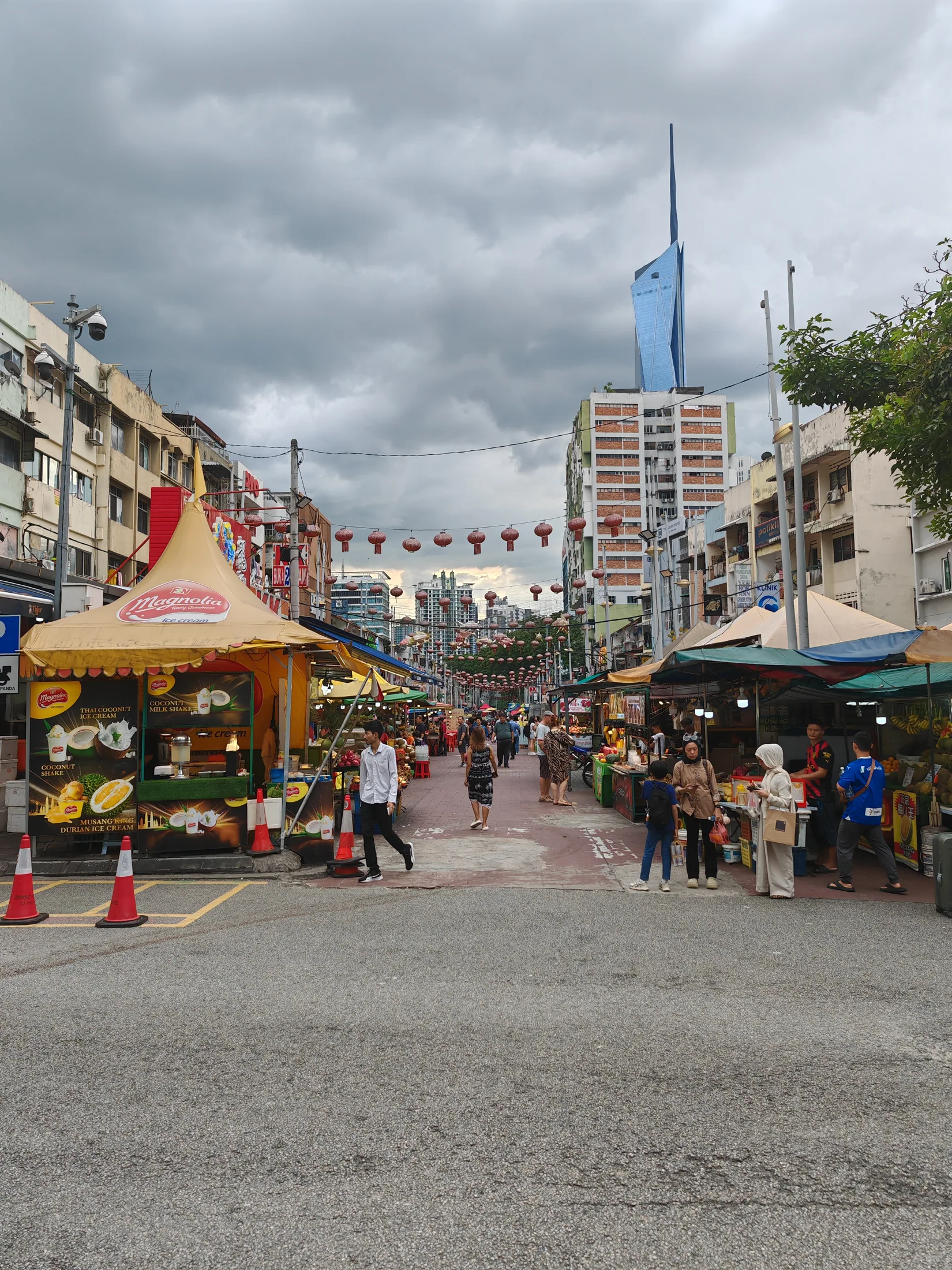 A lively Kuala Lumpur market street beneath modern towers