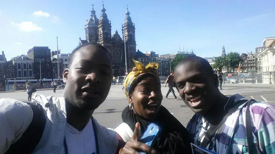 Travellers by an Amsterdam canal with church towers beyond